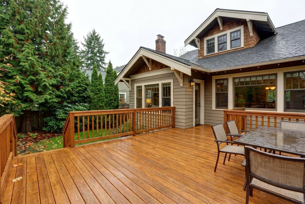 Recently stained backyard deck with railing and patio furniture beside a home in Seattle, WA